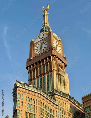 Low angle shot of the Makkah Royal Clock Tower with its golden crescent against a clear blue sky.