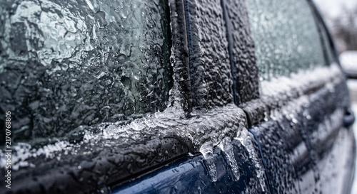 Macro shot of car window completely sealed shut by thick ice and icicles