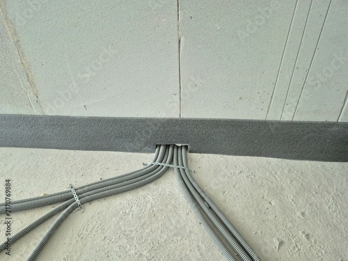 Canvastavla Flexible corrugated conduits fixed on a concrete floor passing under wall insulation of a lightweight aerated concrete block wall