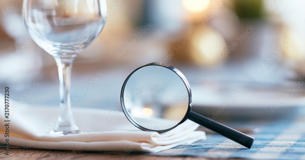 Fototapeta premium Magnifying glass on table with wine glass