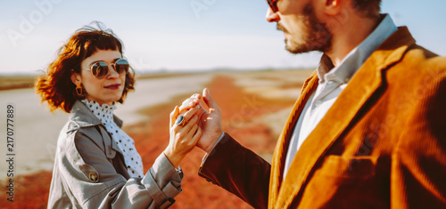Foto Stylish couple walks through a sunny field surrounded by red grass