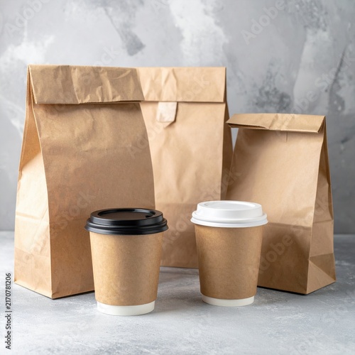 Three brown paper takeaway bags with two coffee cups, takeout lunch delivery, zero waste packaging concept