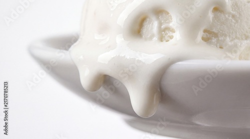 Close up of glossy white cream dripping over a pristine plate, ideal for food styling, dairy, and dessert photography