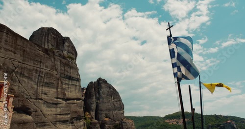 A view of the rounded boulders Meteora rock formations in Thesally region northwestern Greece with the greek flag waving in the wind