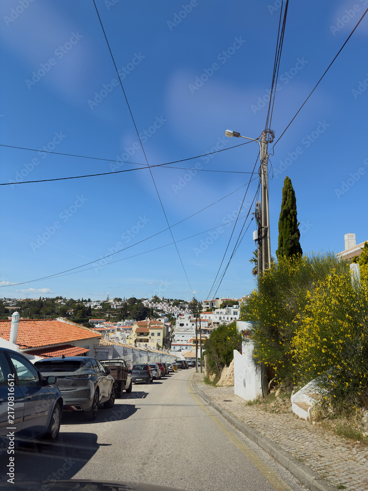 Naklejka premium Hillside street with parked cars in Portuguese coastal town