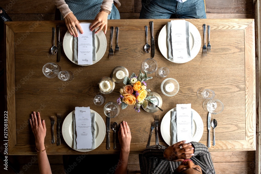 Obraz premium Top view of a dining table set for four with menus and floral centerpiece.