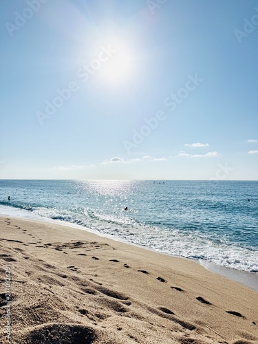 Cuadro en lienzo Sunny beach with footprints, clear blue sky and sparkling sea