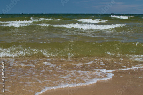 Photography Sea waves with white foam washing onto a sandy beach
