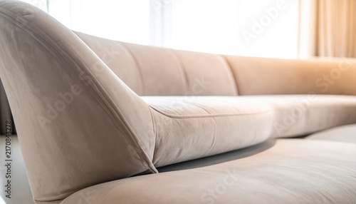 Beige, modern curved sofa in a well-lit living room with soft light and cozy ambiance
