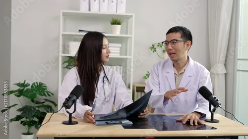 Asian male and female doctors holding an X-ray film, discussing medical diagnosis during a healthcare podcast interview. Recording an educational audio broadcast in a modern clinic studio setting