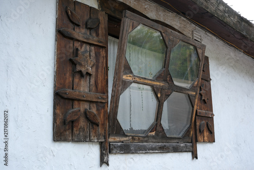 Vintage carved wooden window frame with open shutters on old house