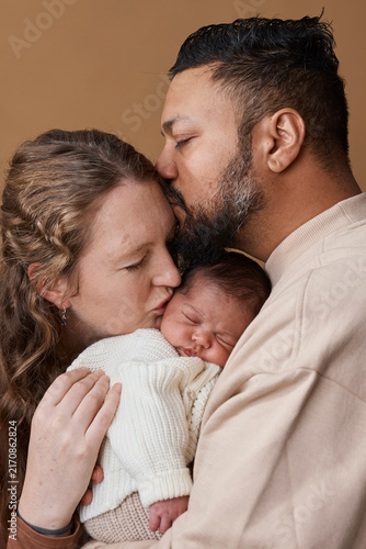 Loving Multiracial Parents Holding Newborn Baby Close in Tender Family Portrait Embrace