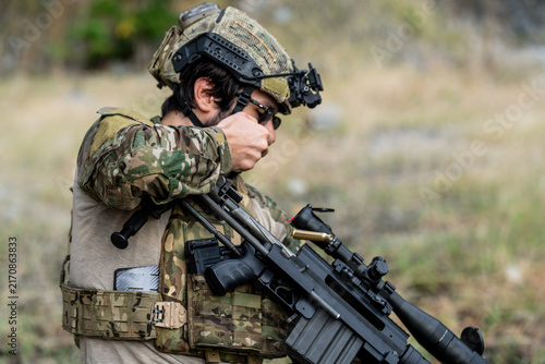 фотографія Soldier prepares weapon at training site in outdoor setting during daytime hours