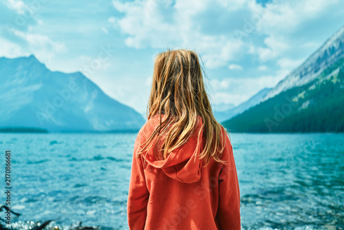 Boy standing beside a turquoise mountain lake
