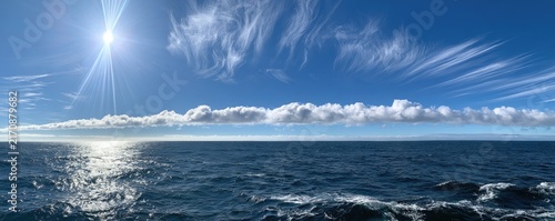 Bright sun shines on vast ocean with dramatic clouds and shimmering reflection