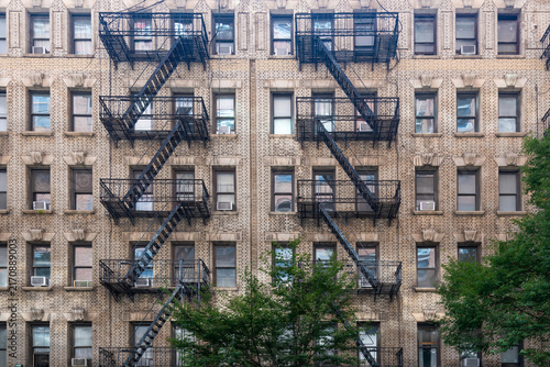 Konstfotografi A close-up view of the symmetrical brick facade of a traditional New York residential building, complete with a network of external fire escapes in the Chelsea neighborhood of Manhattan