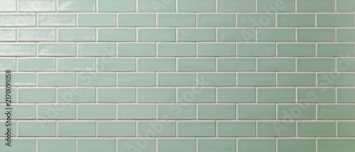 Close-up of a perfectly aligned seamless pattern of shiny, rectangular mint green subway tiles with light grey grout, creating a clean, modern, and minimalist backdrop ideal for