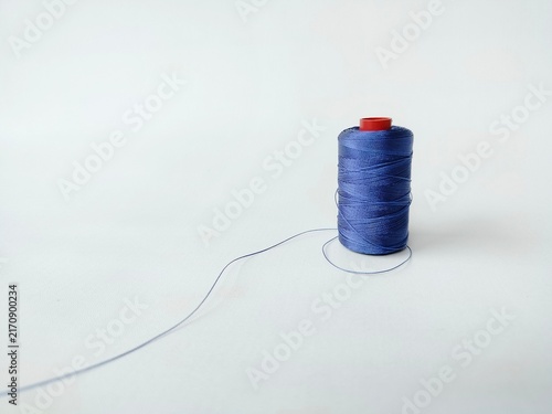 Cuadro en lienzo blue sewing thread spool on white background with loose thread