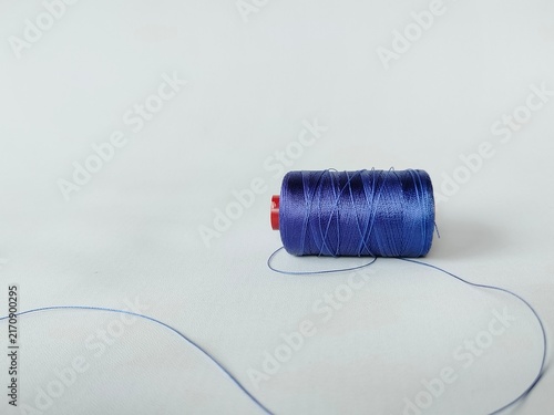 Cuadro en lienzo blue sewing thread spool on white background with loose thread