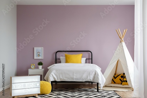 Children bedroom interior with a purple wall metal frame bed yellow pillows and a play teepee interior lavender nightstand sunlight furniture residential property domestic sleeping