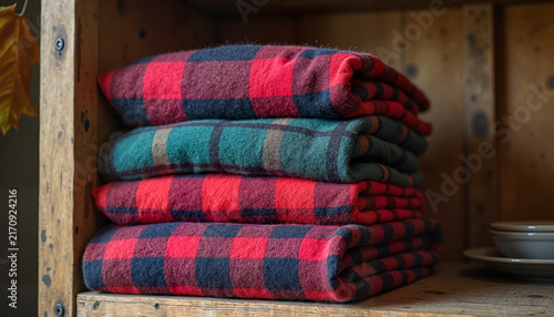 Stacked plaid blankets on wooden shelf
