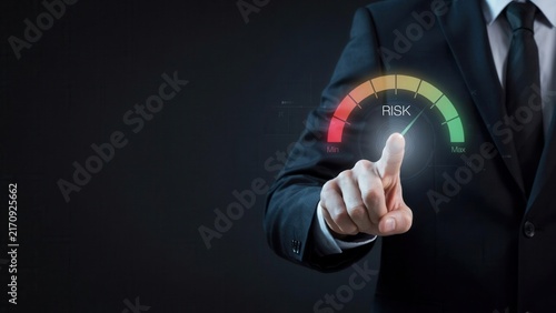 Professional businessman in dark formal suit touches a glowing digital risk gauge interface showing levels from minimum to maximum intensity