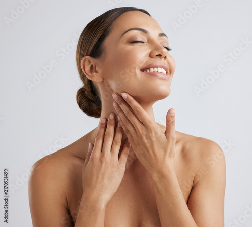 Beautiful smiling woman touching clean healthy skin on neck