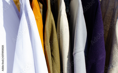 Clothing hanging on hangers. A selection of shirts and sweaters. Outerwear, a variety of options.