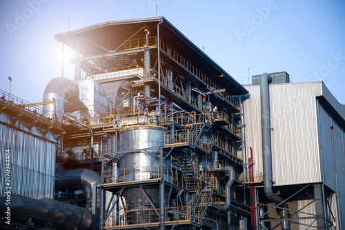 Quadro su tela Modern industrial power plant with complex piping and steel structures under a clear sky