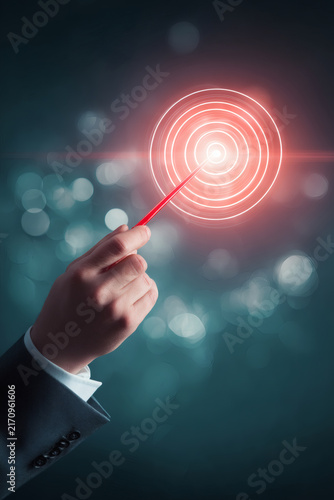focus on a professional hand and a red dart aimed at a golden target icon that emits a powerful beam of light from the center. The target icon features concentric rings representing KPI and 