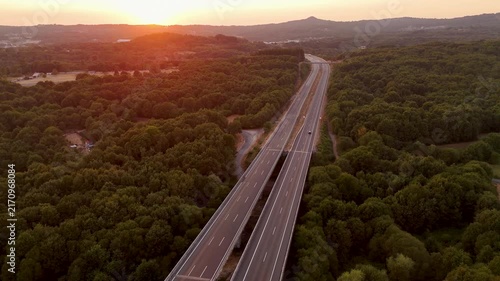 Aerial view of a highway crossing a dense forest at sunset