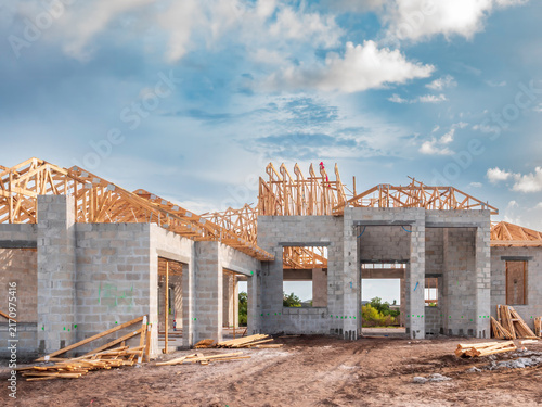 Concrete shell of an upscale, hurricane-resistant house under construction, with framework roof in progress, in a suburban residential development on a sunny morning in southwest Florida. Street view.