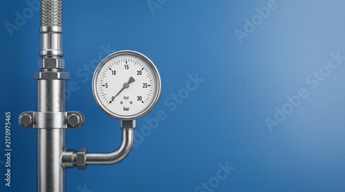 Pressure gauge connected to steel pipes against a blue metal industrial background.