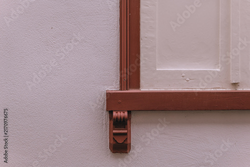 Window detail on a wall showing wooden trim and a small support piece