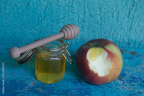 Honey in a jar, apple and honey dipper on blue background