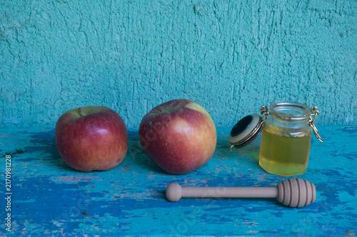 Honey in a jar, apple and honey dipper on blue background