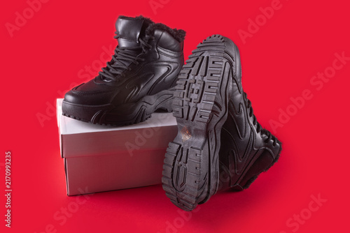 Winter warm black leather sneakers isolated on red background