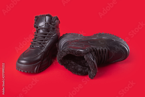 Leather classical sneakers with fur isolated on red background. Winter high lace-up boots.