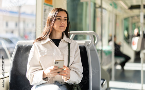 Girl in modern tramway car. Passenger with smartphone rides on half-empty tram carriage