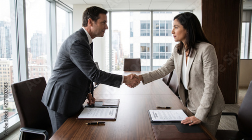 Business Executives Shaking Hands Over Signed Contract In Office Meeting