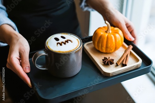 barista serving pumpkin spice latte with ghost foam art. Halloween coffee treat