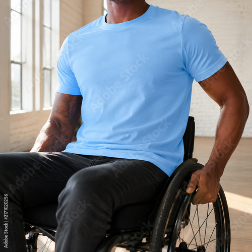 A person in a wheelchair wearing a blue shirt, embodying strength and resilience in a bright, open space.