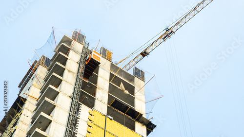 Fotografie High rise building under construction with tower crane and temporary scaffolding