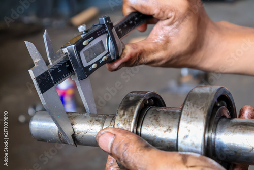 Foto Mechanic Measuring Steel Shaft Diameter with Digital Caliper.