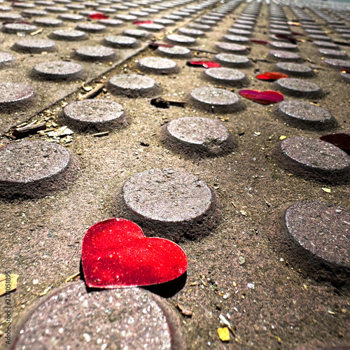 Bild auf Leinwand Red heart-shaped objects are scattered across a textured surface with circular patterns