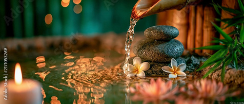 Serene water flowing over stones, surrounded by flowers and candles, creating a tranquil ambiance for relaxation.