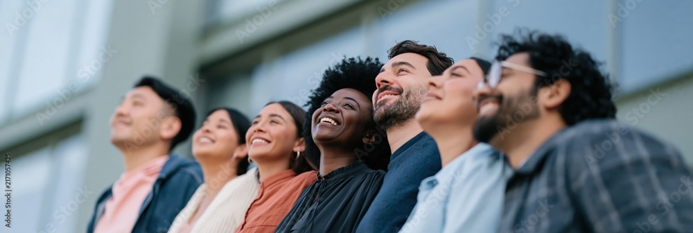 Obraz premium Diverse group of smiling adults standing outside a modern corporate building for team banner and business background