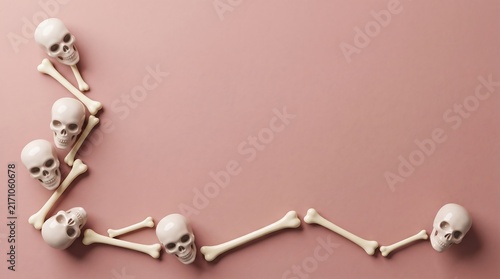 A creative border made of human skulls and bones arranged on a soft pink background for halloween design