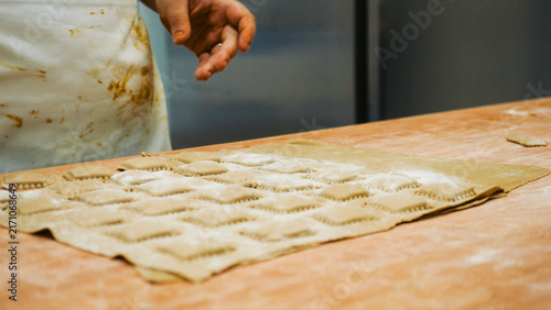 Foto A chef's hands prepare fresh tortelli, a classic filled pasta, on a floured wood