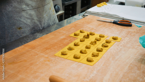 Quadro su tela Preparing traditional tortelli pasta with filling on a wooden board, showcasing